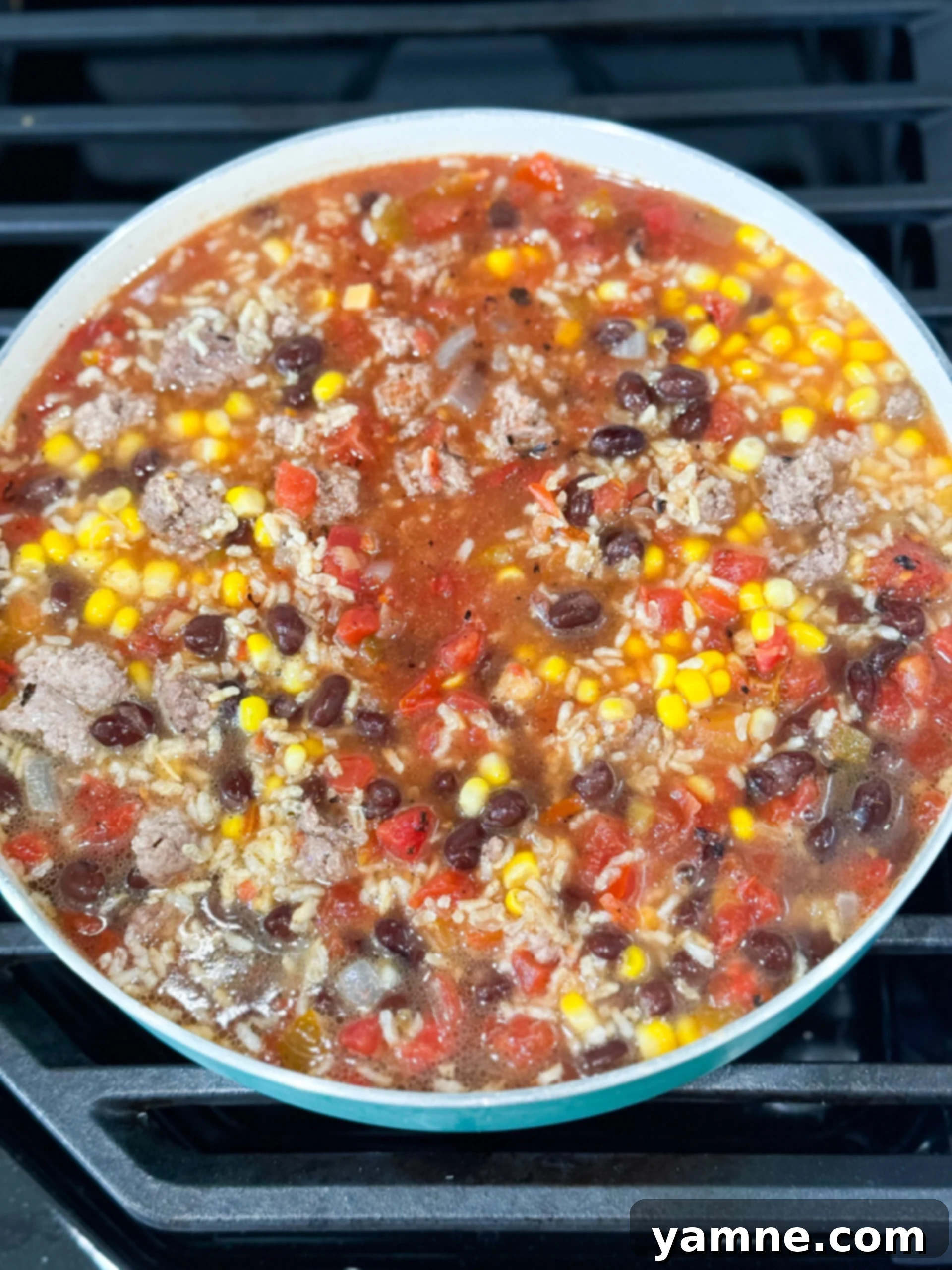 Rice, beans, salsa, and corn simmering together in a large pot, releasing aromatic steam and blending flavors.