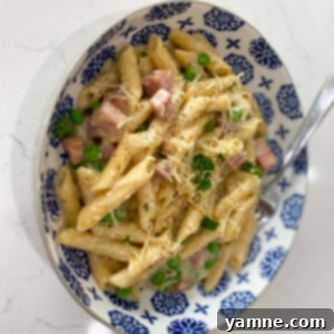 Delicious one-pot ham and noodle meal with creamy white sauce, ham, peas, and penne pasta, garnished with fresh parsley