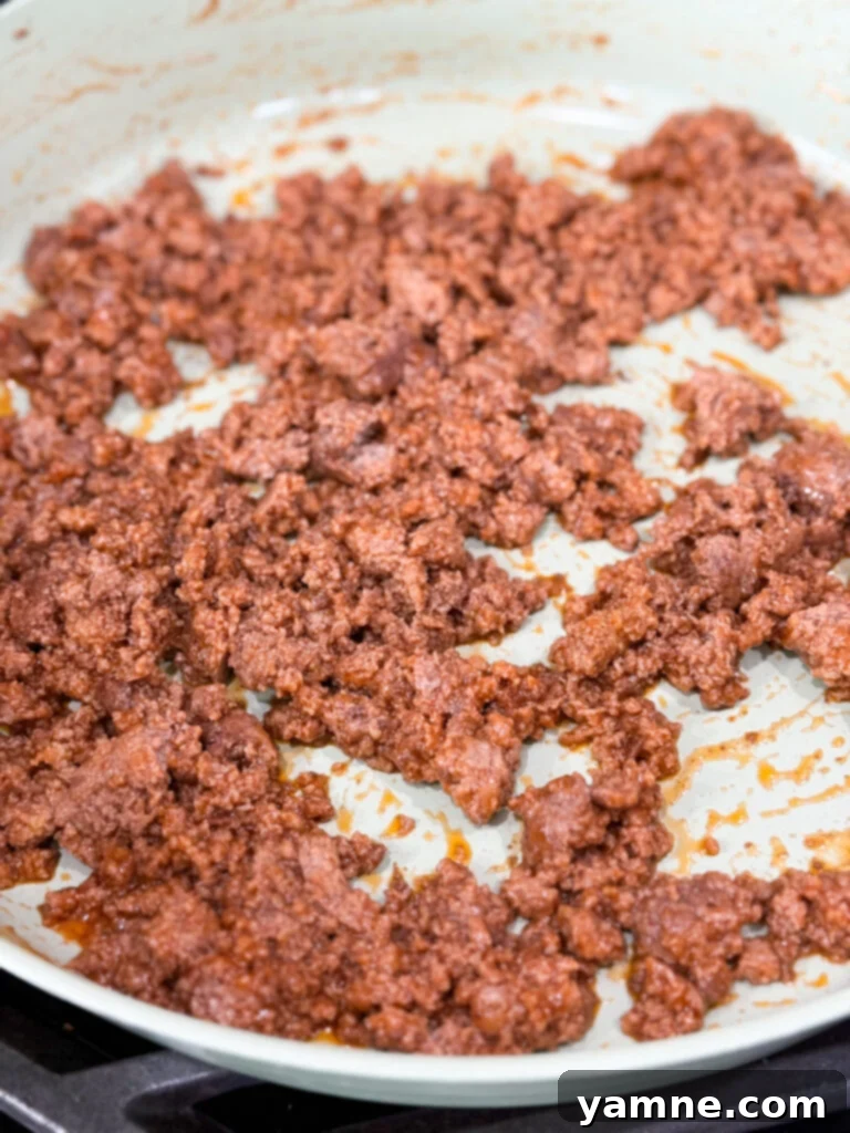 Ground meat cooked in sloppy joe sauce in a large white skillet on the stove top