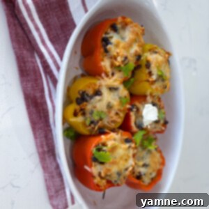 Colorful bell peppers generously stuffed with a savory taco rice and chicken filling, topped with melted cheese, ready to be served.