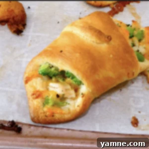 Cheesy Chicken Broccoli Crescents 2 Golden brown chicken broccoli cheese crescent rolls on a baking sheet, ready to serve.