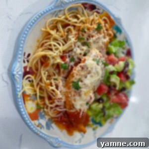 Crispy, saucy, and cheesy Slow Cooker Chicken Parmesan served over spaghetti with fresh herbs.