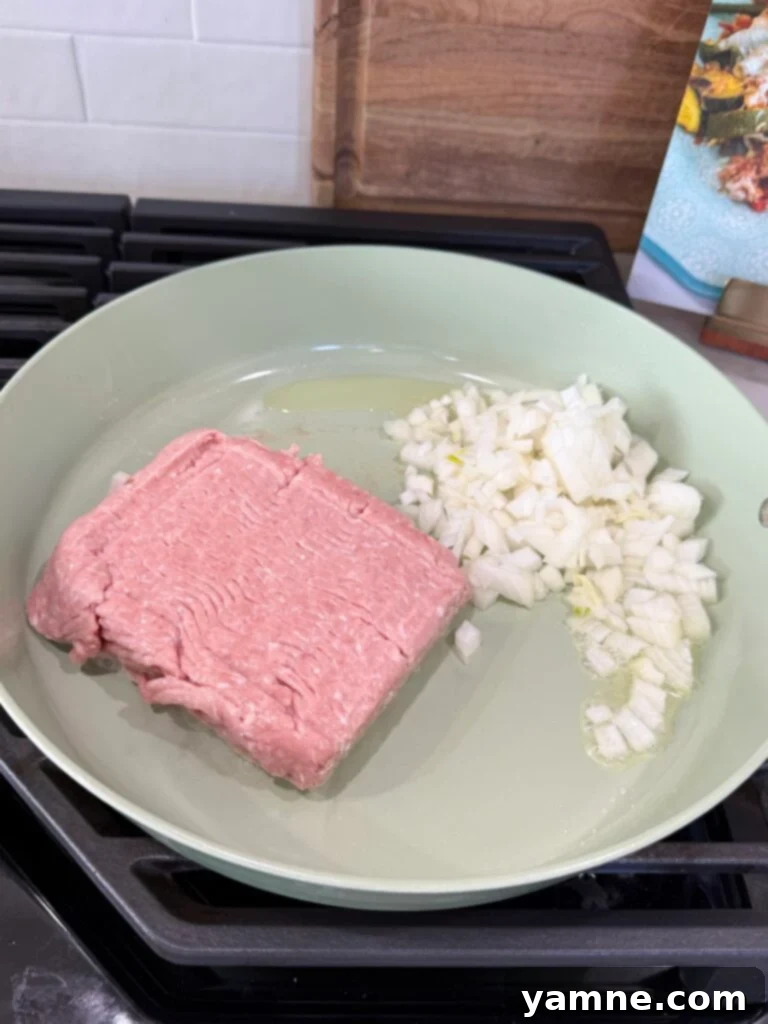 Healthy Turkey and Veggie Skillet 4 Adding ground turkey to a hot skillet with diced onions