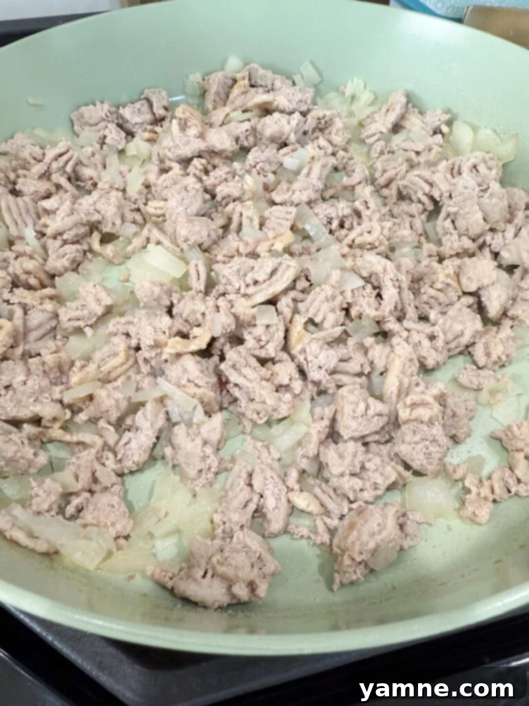 Healthy Turkey and Veggie Skillet 5 Ground turkey browning in a skillet with onions, being broken apart with a spatula