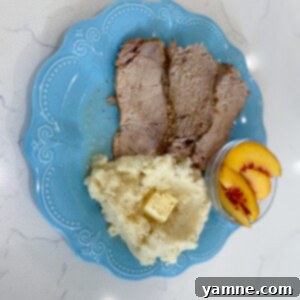 A perfectly cooked slow cooker balsamic pork loin, sliced and drizzled with a rich balsamic glaze, served with a side.