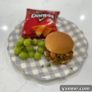 A delicious, overflowing lentil sloppy joe sandwich on a toasted bun.