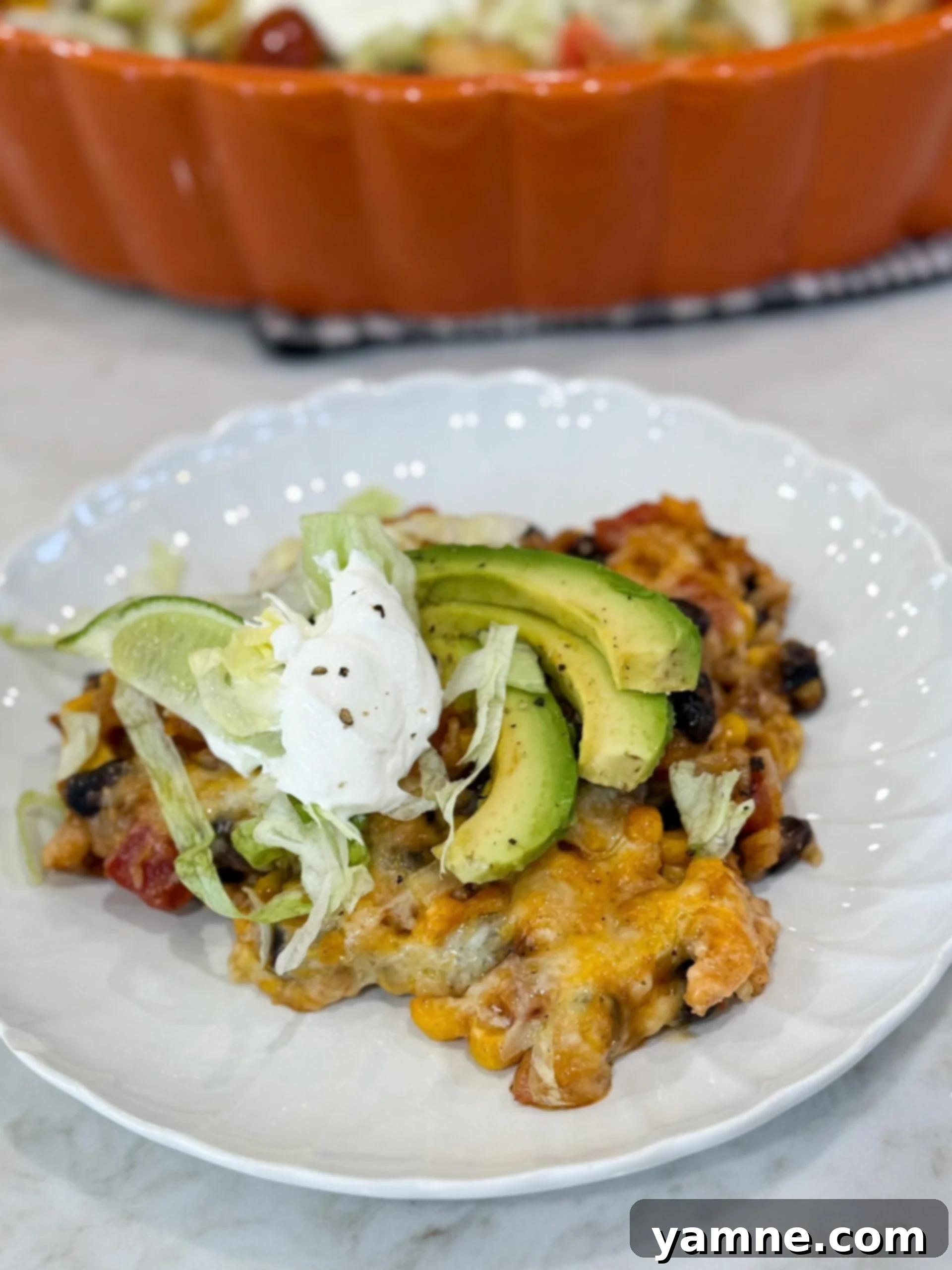 Fiesta chicken casserole on plate with melted cheese and fresh toppings