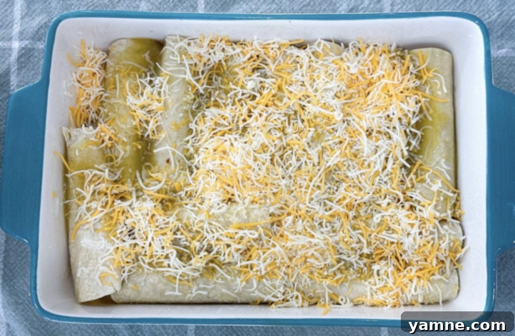 Ultimate Green Chile Chicken Enchiladas 6 Green chili chicken enchiladas covered with sauce and cheese, ready for the oven.