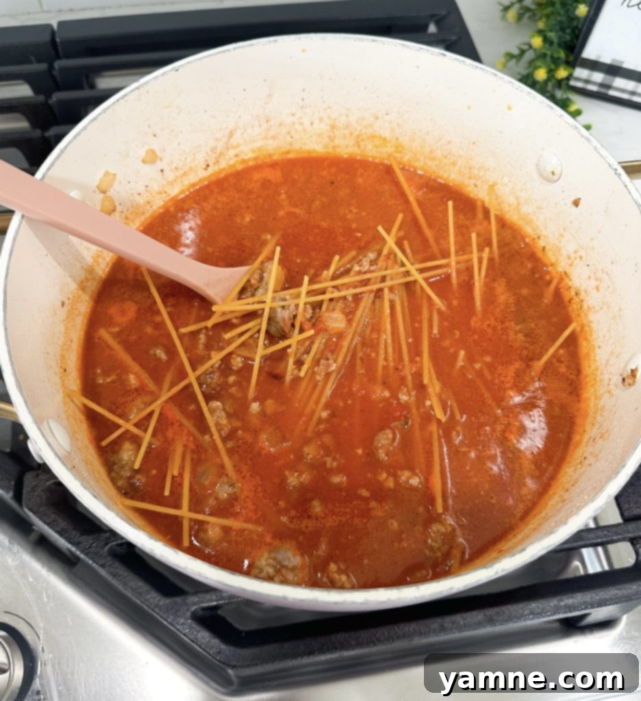 Adding broth to browned sausage and onions, scraping the bottom of the pot.