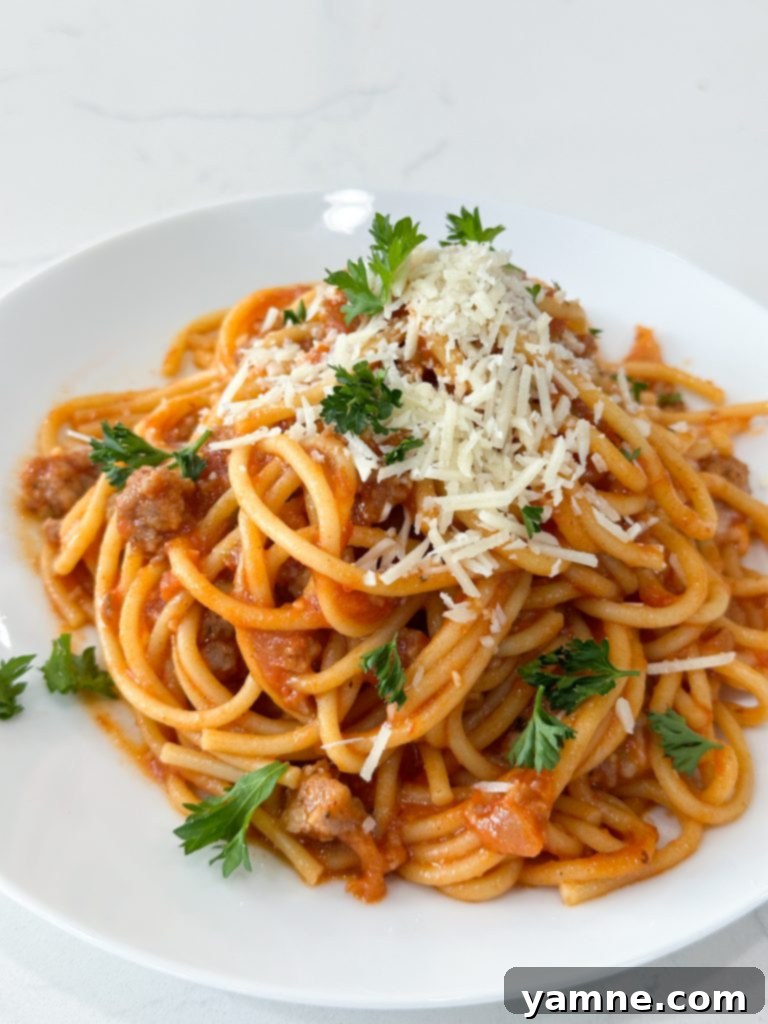 Finished one-pot spaghetti with sausage, garnished with cheese.