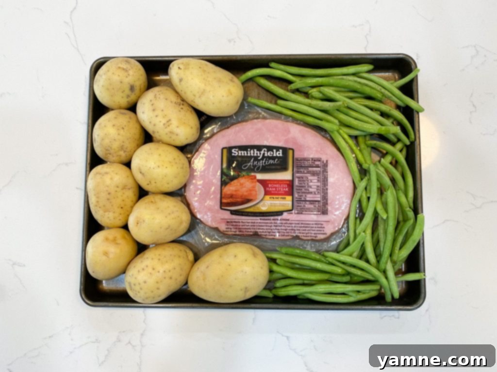 One-Pan Honey Mustard Ham, Green Beans, and Potatoes 2 Close-up of Sheet Pan Honey Mustard Ham, Green Beans, and Potatoes fresh out of the oven, showing golden brown ham, tender green beans, and roasted potatoes coated in a sticky glaze.