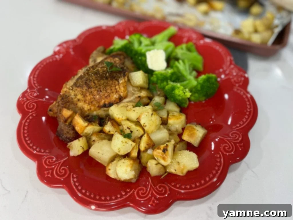 Sheet Pan Greek Chicken Thighs and Potatoes with lemon wedges and fresh herbs.