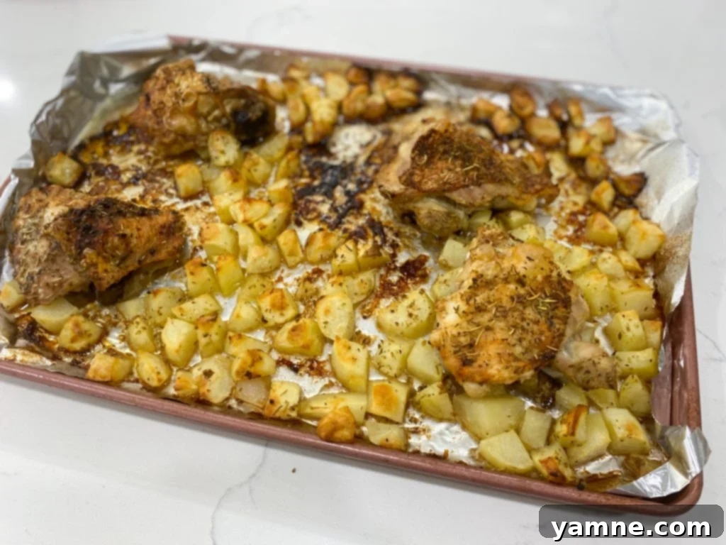 Close-up of seasoned raw chicken thighs and diced potatoes in a bowl, ready for the oven.