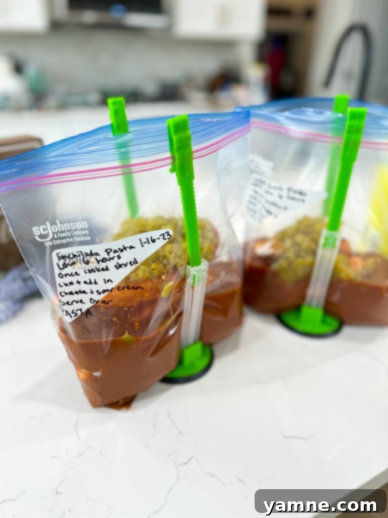 Cheesy Crockpot Enchilada Pasta 5 Frozen freezer bag containing chicken, enchilada sauce, and spices, labeled for future cooking.