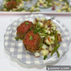 One-Pan Cheesy Stuffed Meatloaf and Roasted Veggies 5 A close-up of a perfectly cooked mozzarella stuffed meatloaf, with melted cheese peeking out, served on a plate.