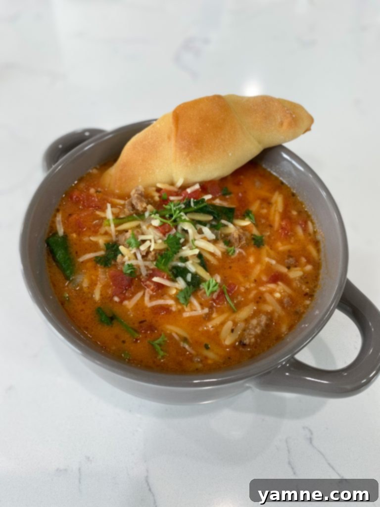 bowl of sausage orzo soup with a spoon
