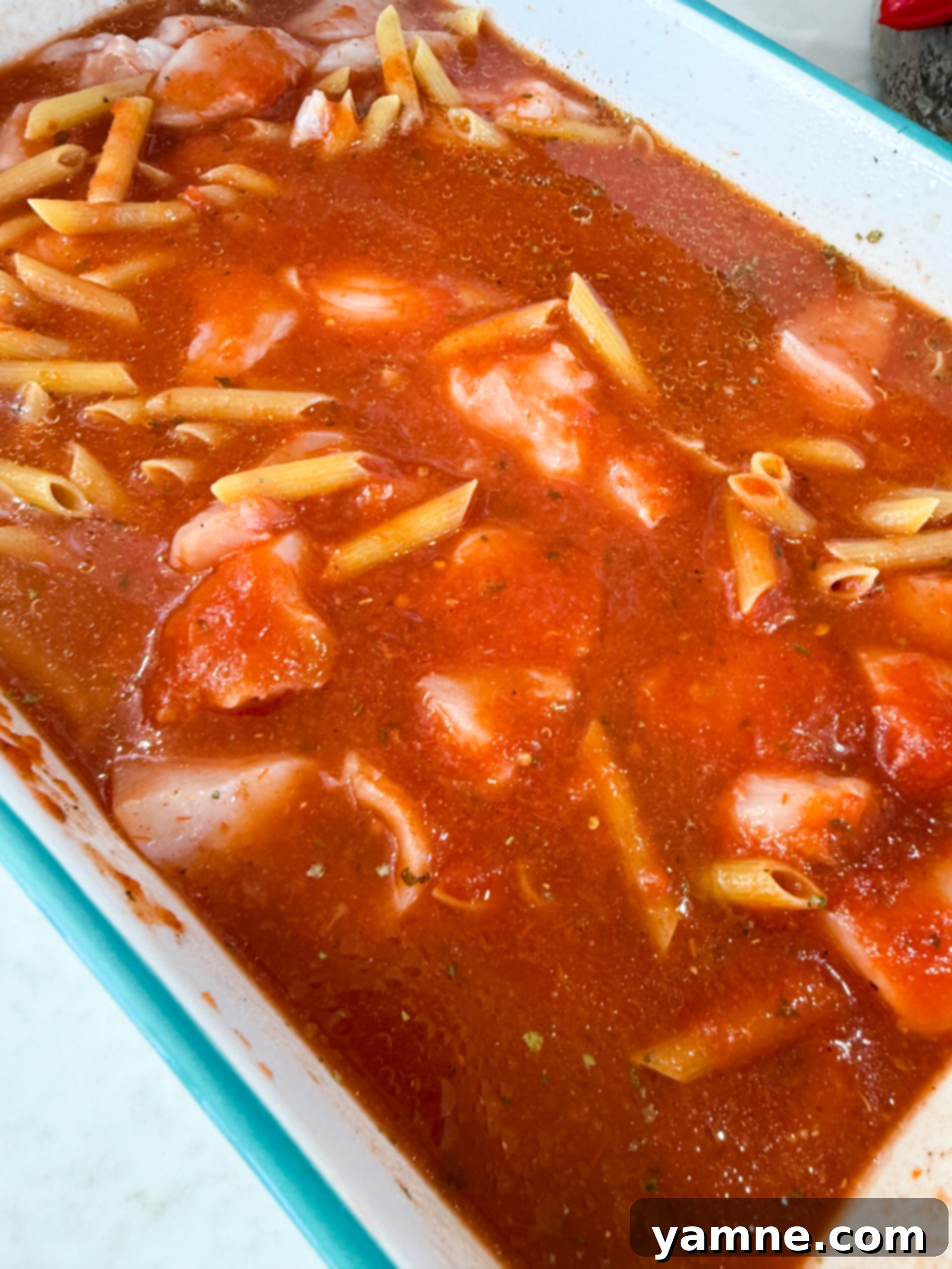 Cheesy Chicken Parm Bake 6 Mixing pasta, sauce, and chicken in baking dish