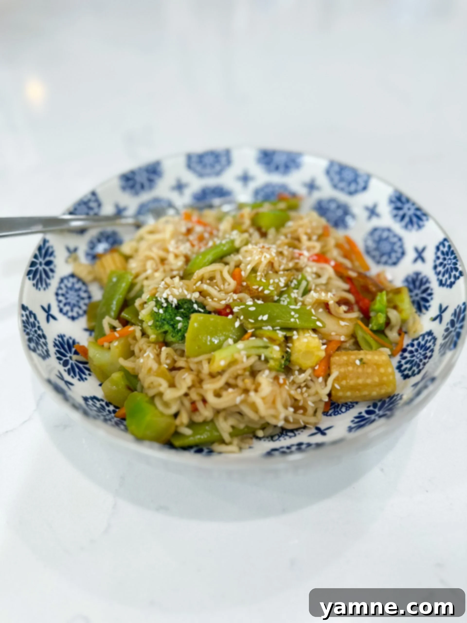 Close-up bowl of ramen noodle stir fry with colorful vegetables and sauce