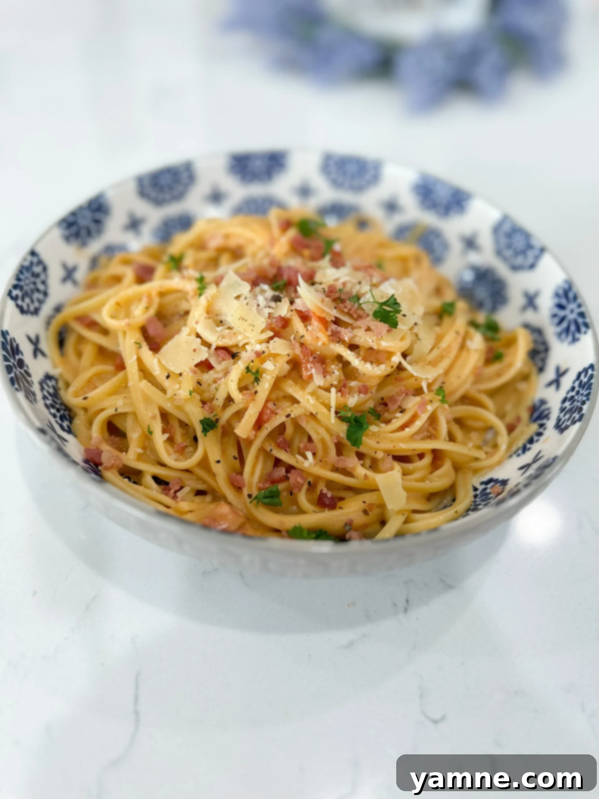 Smoky Bacon Tomato Cream Pasta 2 Creamy tomato bacon pasta in a white bowl with fettuccine noodles and bacon bits
