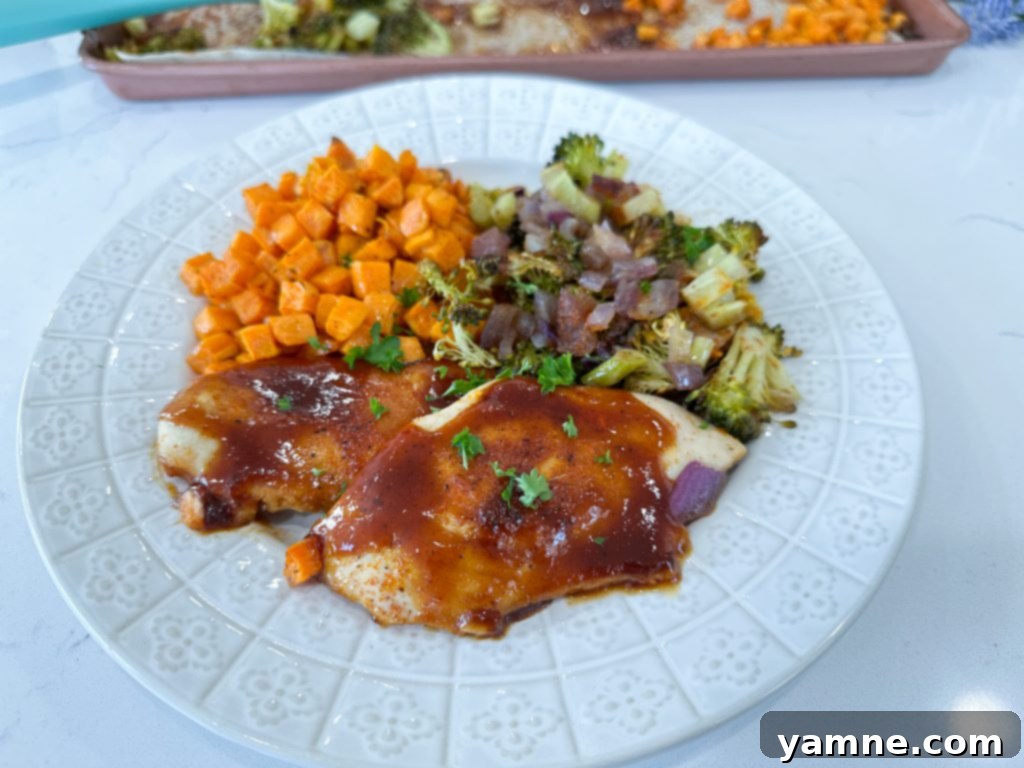 Finished Sheet Pan BBQ Chicken and Vegetables, garnished with fresh herbs, showcasing the golden-brown chicken and tender roasted vegetables.