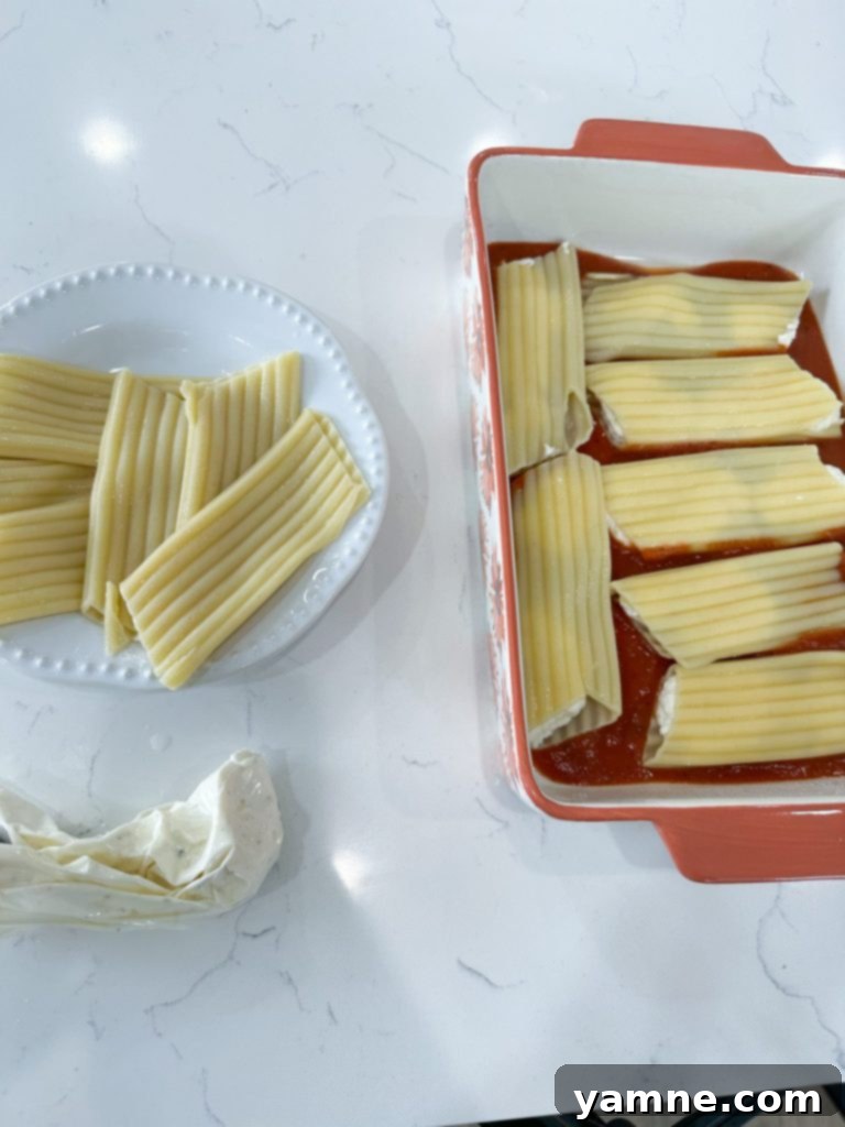 Ingredients for cheese manicotti laid out, including pasta, cheese, sauce, and spices.