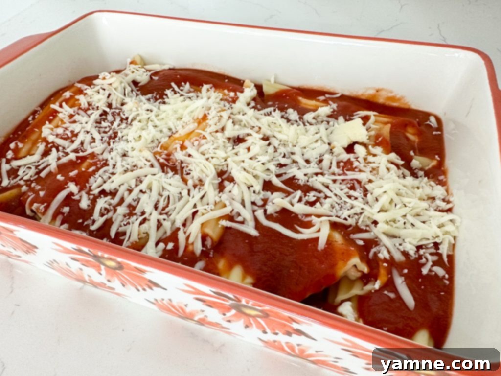 Baking dish filled with cheese manicotti, covered in sauce and mozzarella cheese, ready for the oven.