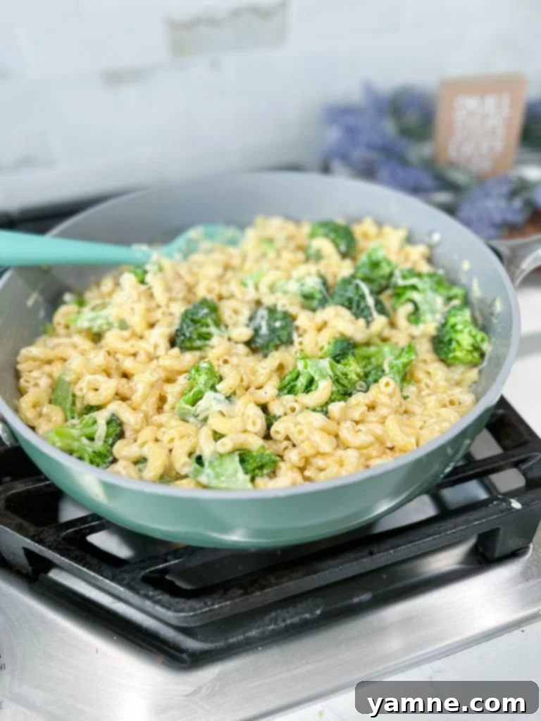 Homemade White Mac and Cheese with tender macaroni, creamy white sauce, and fresh green broccoli florets in a large pot, garnished with parsley.