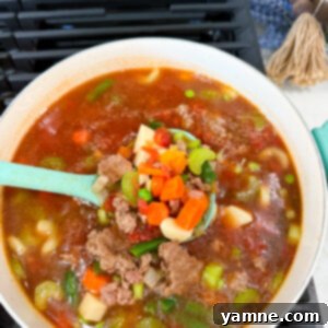 A large, inviting bowl of ground beef and vegetable soup, perfectly cooked and ready to be served, showcasing its rich texture and vibrant vegetables.