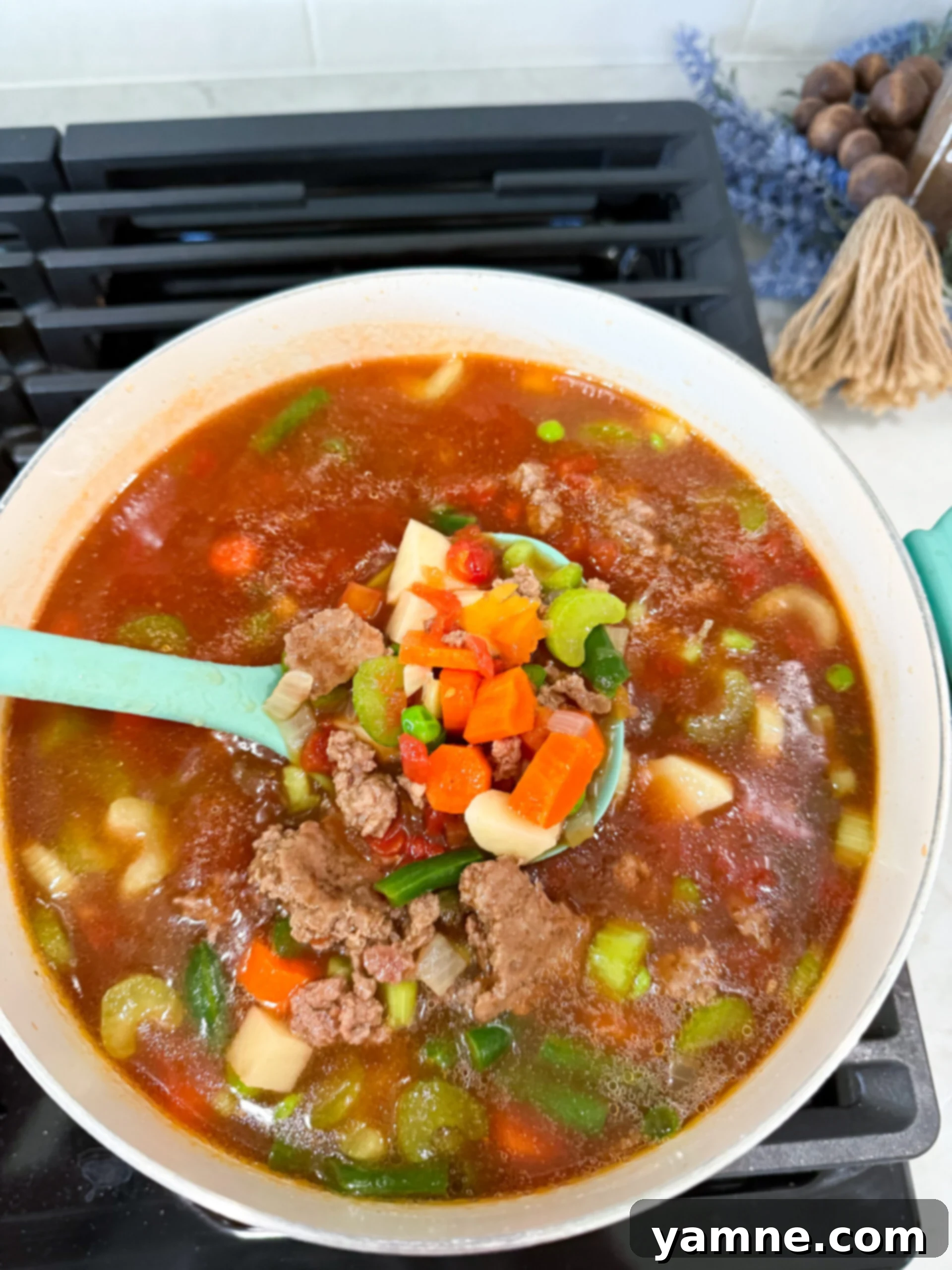 A large, inviting bowl of ground beef and vegetable soup, perfectly cooked and ready to be served, showcasing its rich texture, vibrant vegetables, and steam rising.