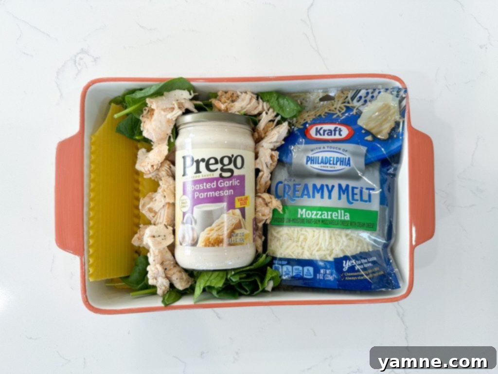 Close-up of baked chicken and spinach lasagna in a white baking dish, showing melted, bubbly cheese and rich layers.