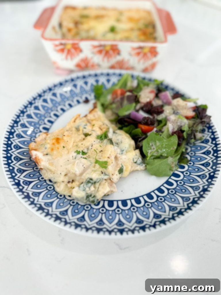 Close-up of a serving of chicken and spinach lasagna on a plate, showing the creamy layers.