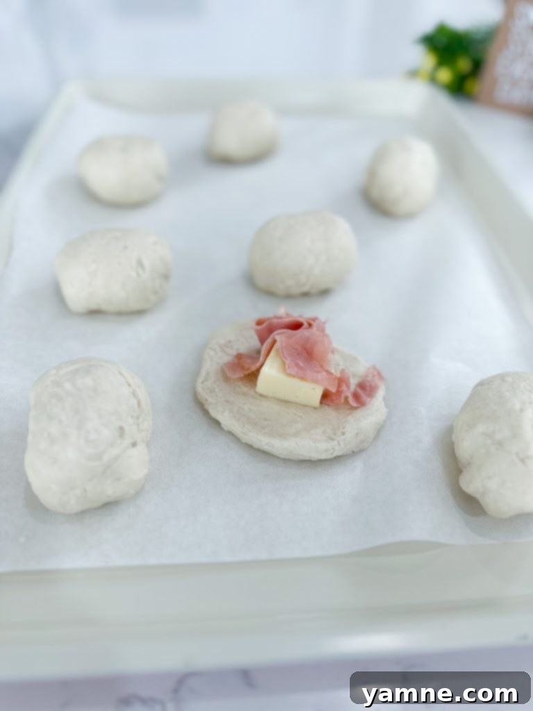 Flattening refrigerated biscuits to prepare for stuffing with ham and cheese.