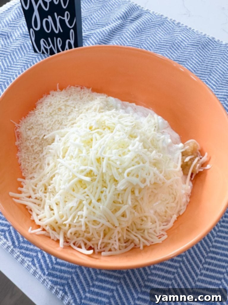 Effortless Slow Cooker Sausage Tortellini Lasagna 4 A bowl filled with a creamy cheese mixture of cottage cheese, mozzarella, Parmesan, and garlic, ready for layering.