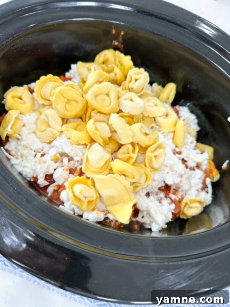 Effortless Slow Cooker Sausage Tortellini Lasagna 5 The inside of a slow cooker, prepared with non-stick spray or a liner, ready for layering ingredients.