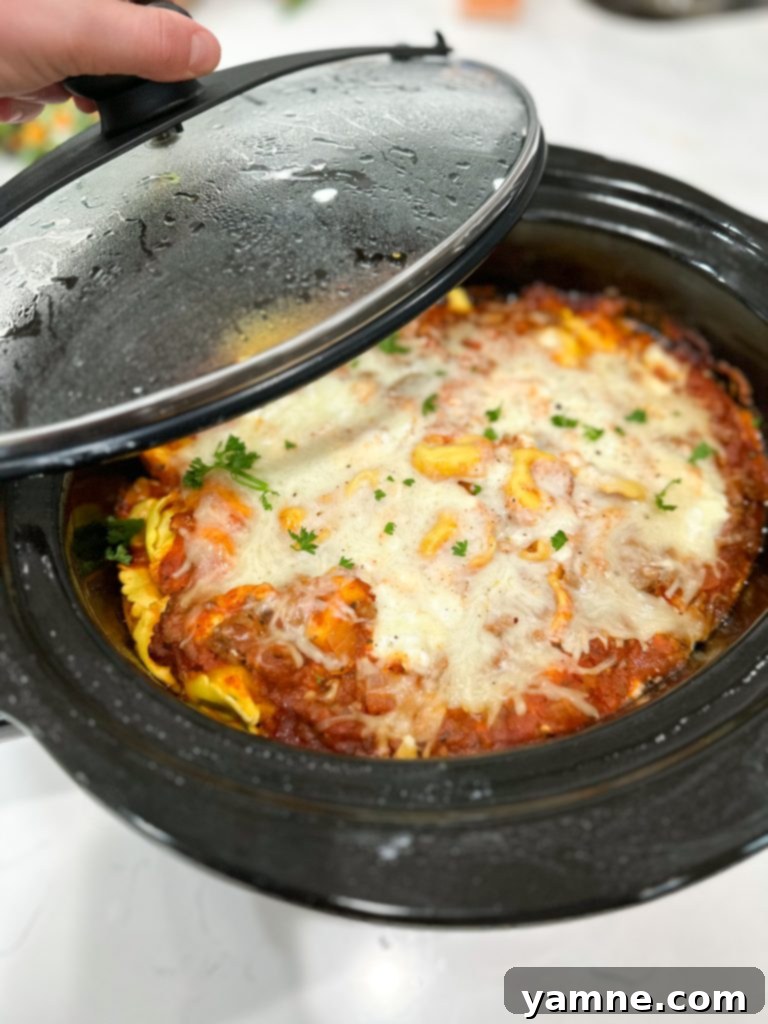 Effortless Slow Cooker Sausage Tortellini Lasagna 7 Slow Cooker Sausage Tortellini Lasagna topped with shredded mozzarella cheese, ready to be cooked.