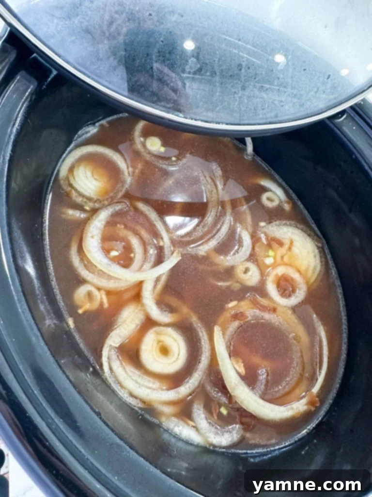 All ingredients loaded into a slow cooker for French Onion Chicken.