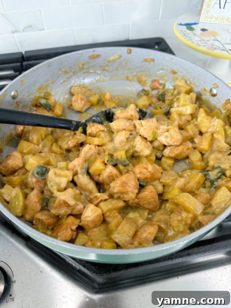 Close-up of green chile chicken and potatoes simmering with melted cheese
