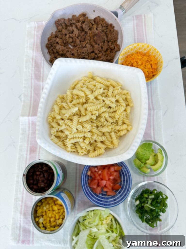 A vibrant Doritos Taco Pasta Salad in a large bowl, showcasing pasta, ground beef, fresh vegetables, and crushed Doritos.