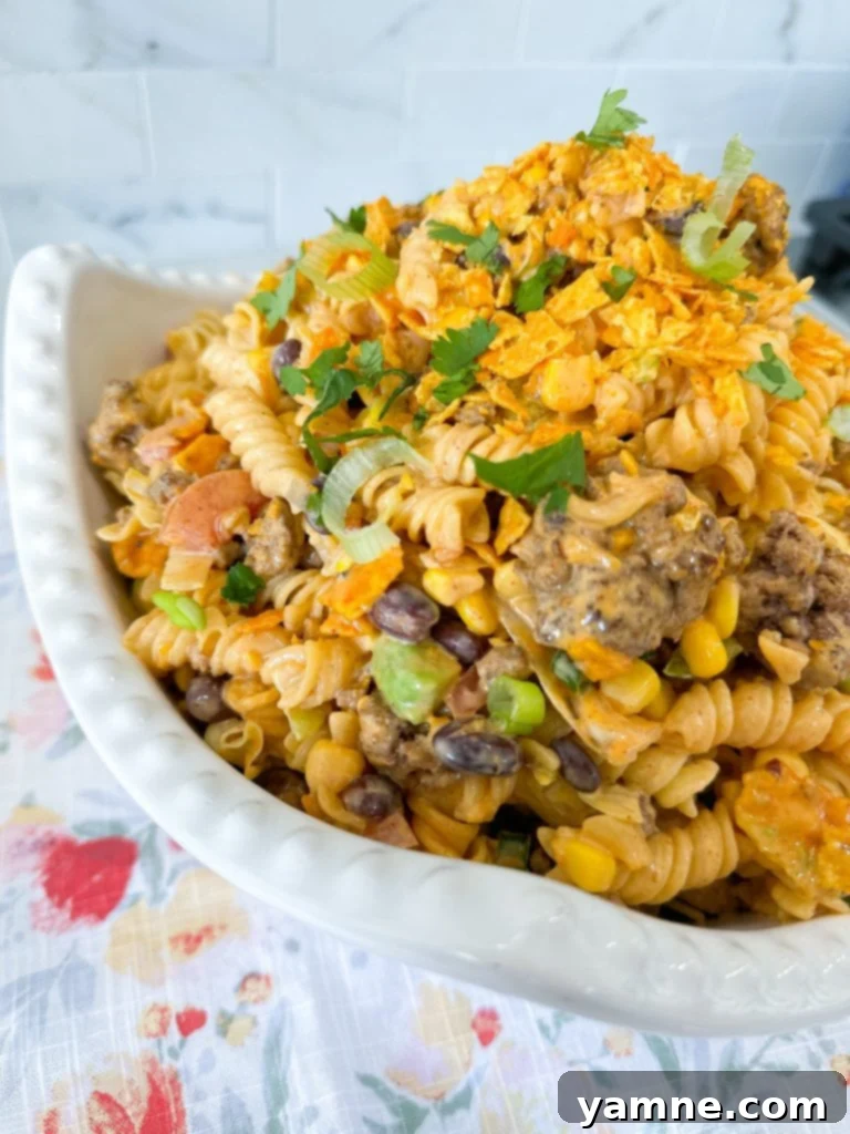 Close-up of Doritos Taco Pasta Salad with a serving spoon.