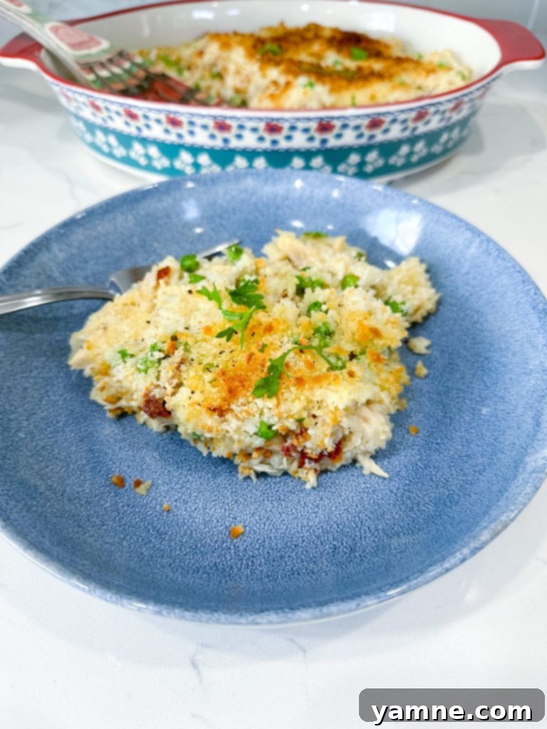 Close-up of ingredients for Chicken Alfredo Rice Casserole including cooked chicken, rice, Alfredo sauce, peas, and sun-dried tomatoes.