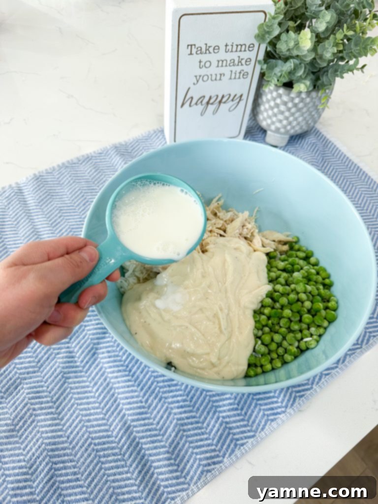 Pouring milk into the casserole mixture.