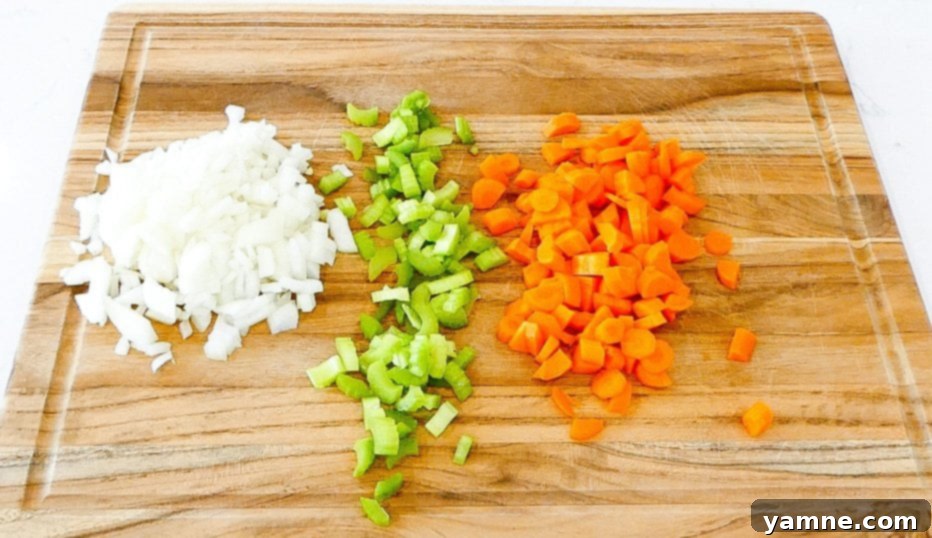 Diced chicken and vegetables being added to a slow cooker, illustrating the initial steps of the recipe.
