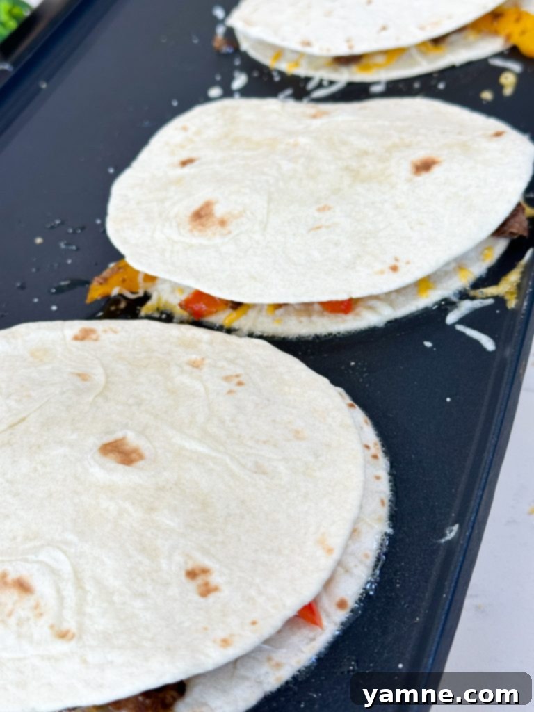 A freshly cooked, golden-brown steak fajita quesadilla being sliced into wedges on a cutting board