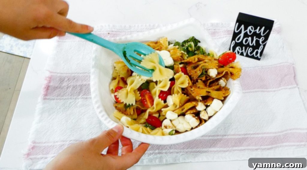 A serving of Caprese Pasta Salad in a white bowl.
