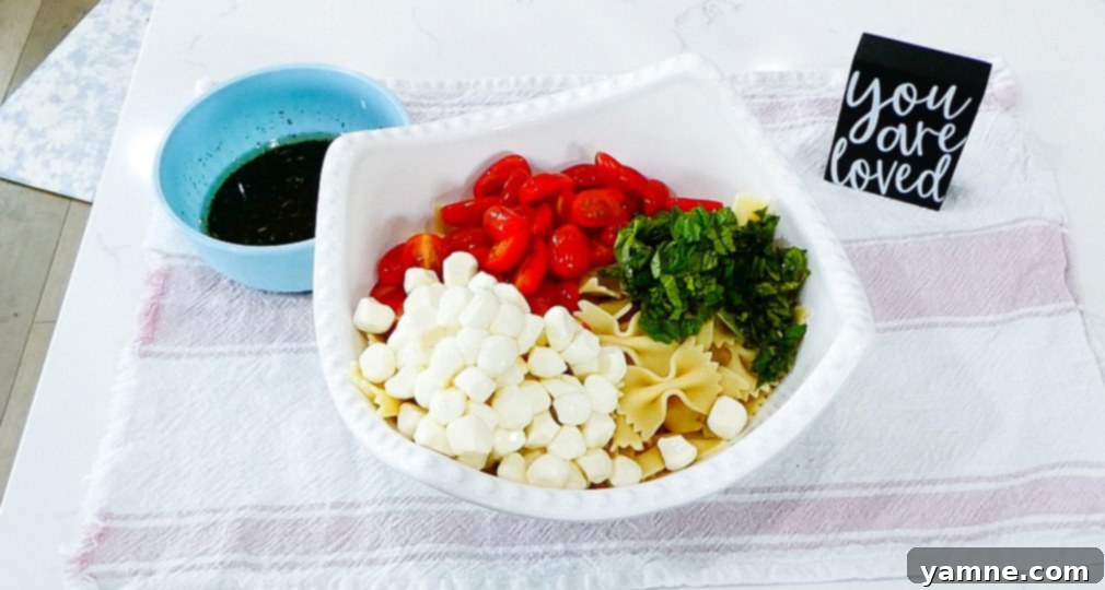 Gently tossing the pasta salad to distribute the dressing.