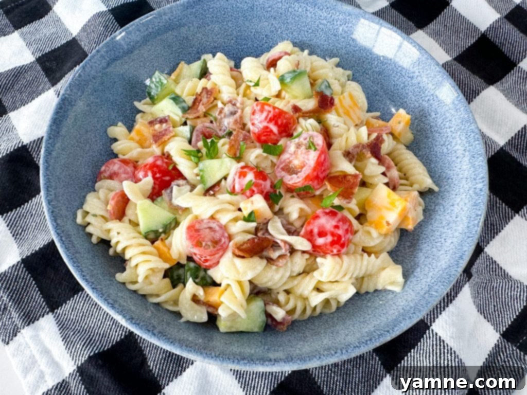 Tuscan Ranch Pasta Salad 2 A large bowl of Italian Ranch Pasta Salad with rotini pasta, bacon, pepperoni, cucumber, tomatoes, and cheddar cheese.