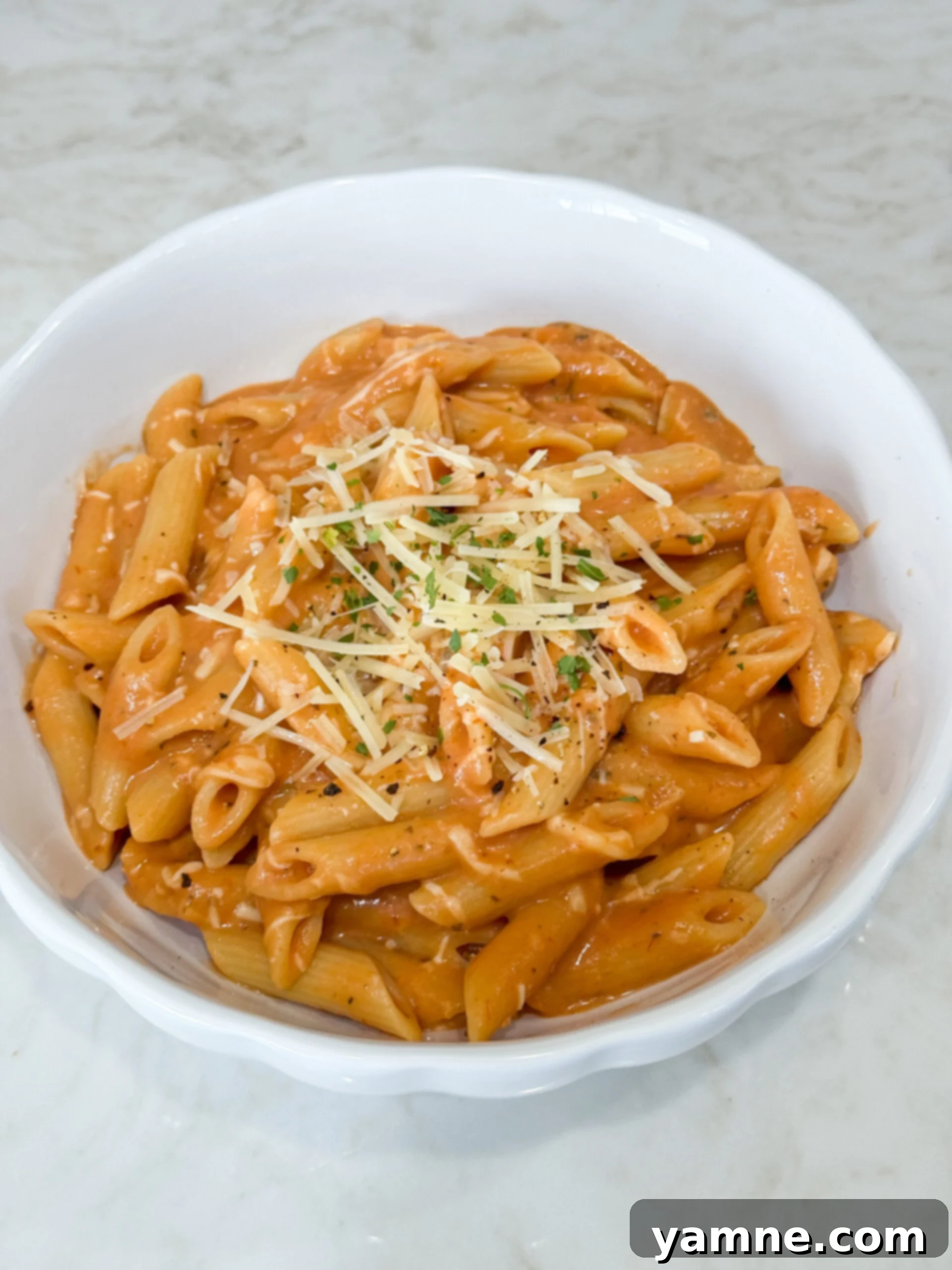 Creamy penne pasta in a pot with melted cheese on top, ready to serve