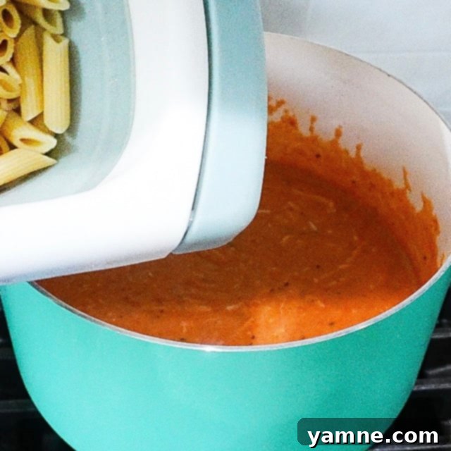 Mozzarella and Parmesan being stirred into creamy sauce in a pot