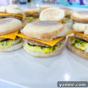Delicious make-ahead breakfast sandwiches stacked with eggs, cheese, and sausage on English muffins.