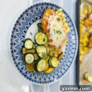 Close-up of baked Sheet Pan Marinara Mozzarella Chicken and Zucchini with perfectly melted cheese and fresh herbs.
